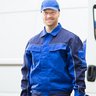 Ein Mann in Arbeitskleidung der vor einem Firmenbulli steht