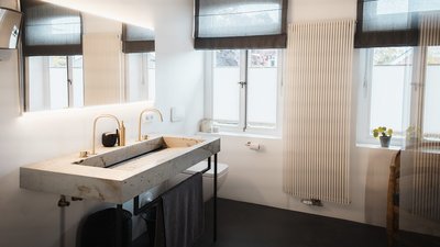 Ein modernes Badezimmer mit einem eleganten Waschbecken aus Beton und goldenen Armaturen, das eine stilvolle Atmosphäre schafft.